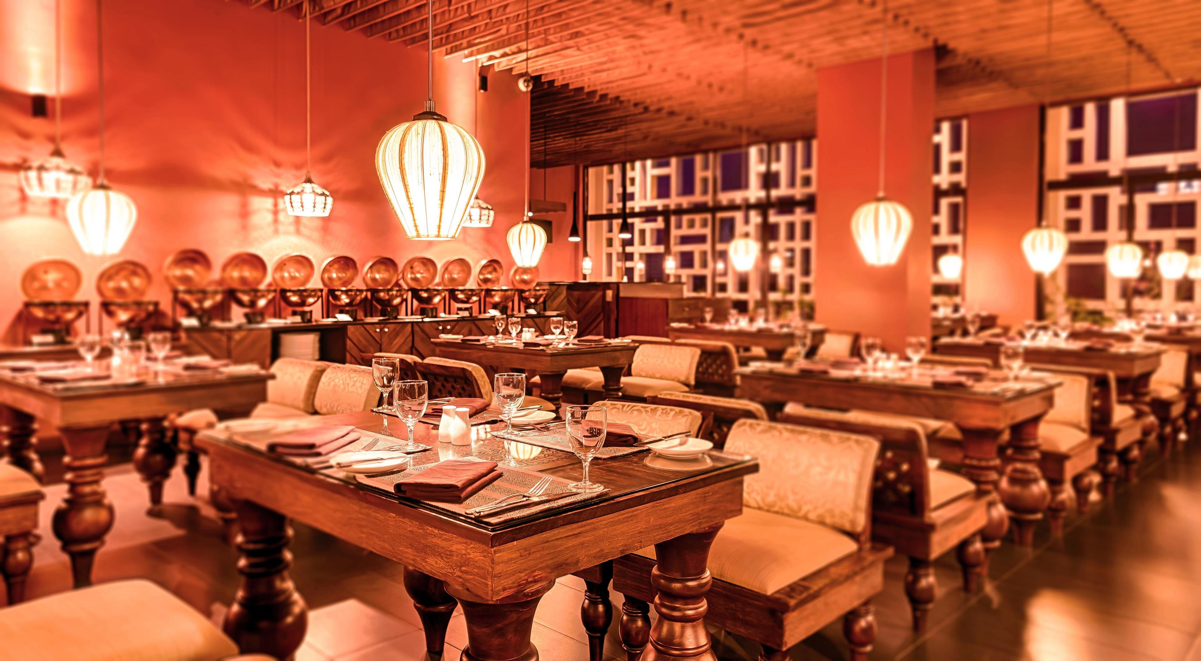 A restaurant with multiple tables and chairs, warm lighting, and a cozy atmosphere.