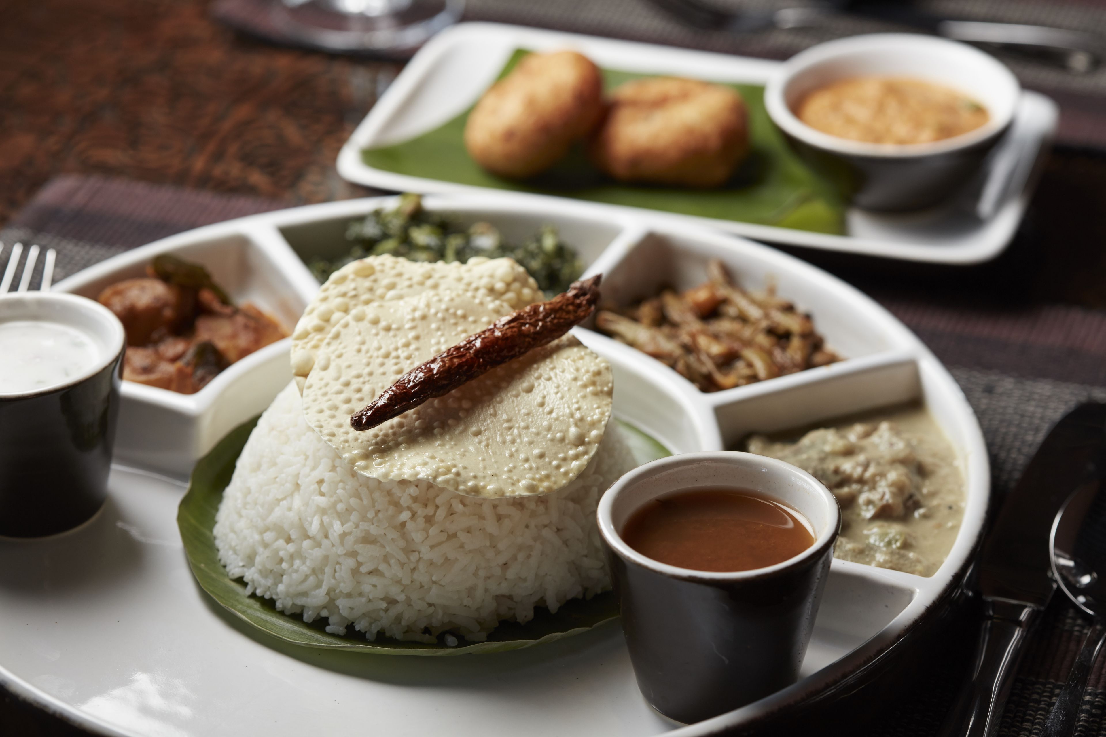 Un repas traditionnel du sud de l’Inde, composé de riz, de lentilles et d’une variété de plats d’accompagnement, servi sur une assiette blanche.