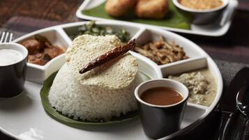 Un repas traditionnel du sud de l’Inde, composé de riz, de lentilles et d’une variété de plats d’accompagnement, servi sur une assiette blanche.