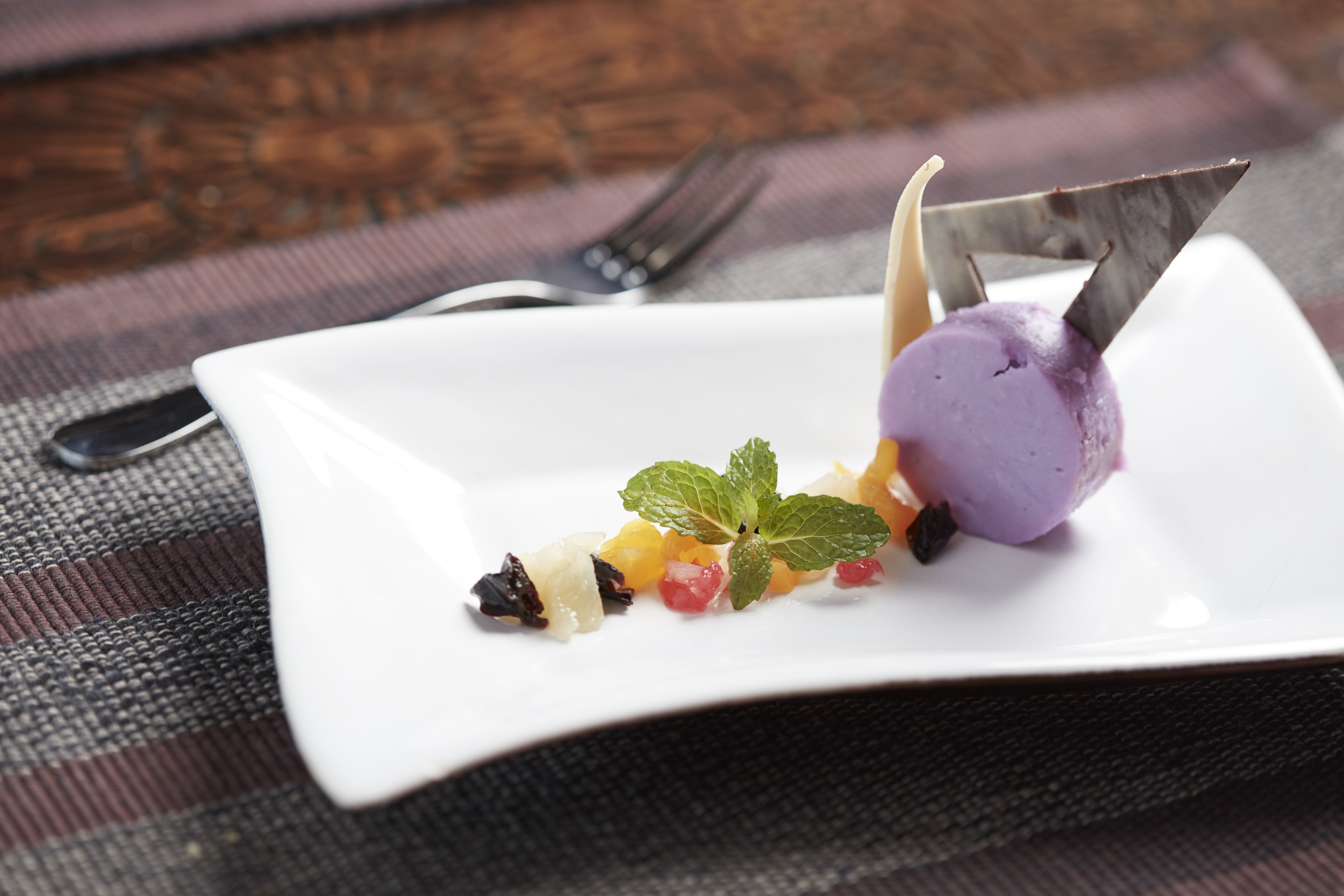 A dessert on a white plate with a fork and knife on a textured tablecloth.
