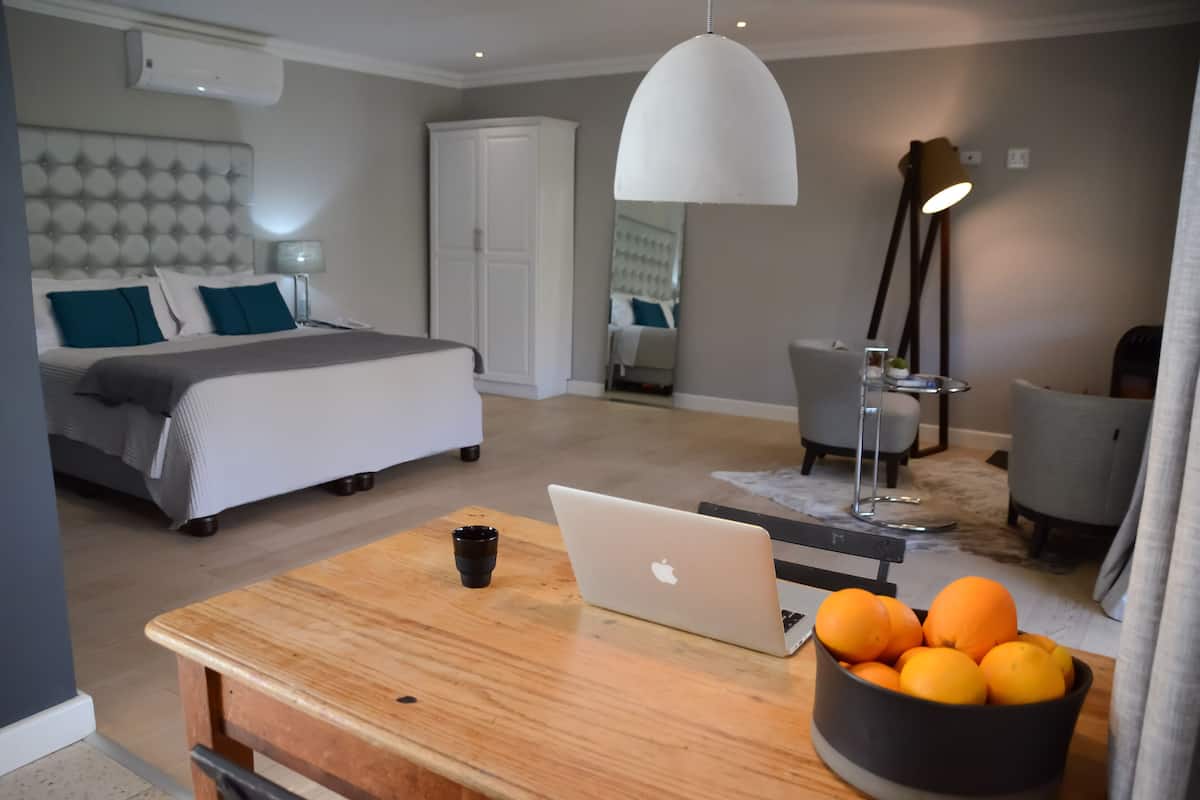 A modern bedroom with a bed, bedside table, laptop, and a bowl of oranges.