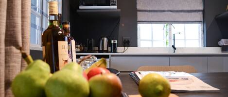 A kitchen counter with fruits, a bottle, and a cutting board.