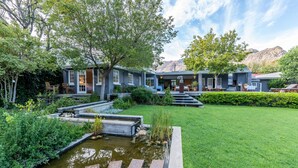 A residential property with a pond, a well-maintained lawn, and a house with multiple rooms and a patio area. - In Abundance Guest House (Montagu)