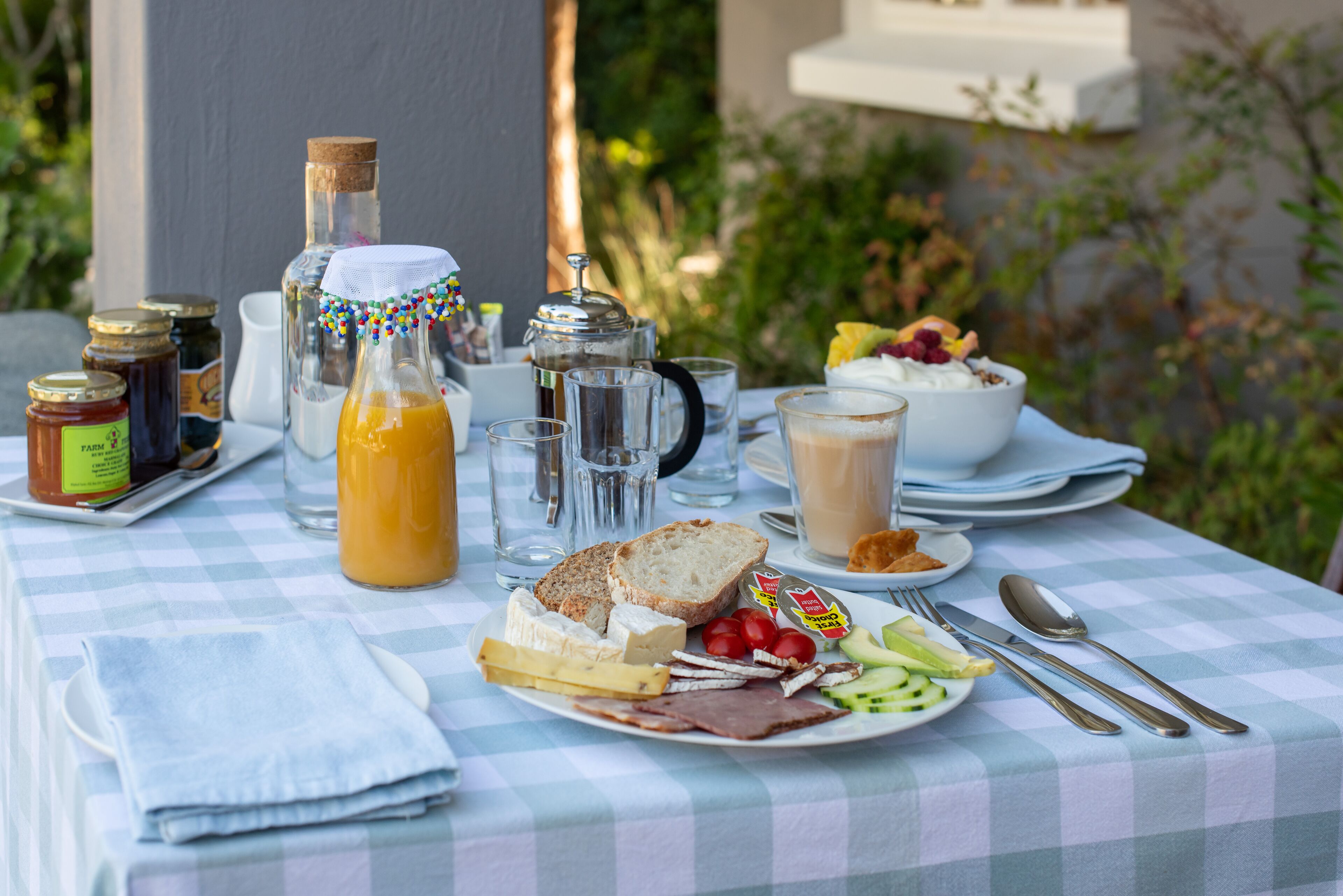 A breakfast table with a checkered tablecloth, various food items, and breakfast beverages.