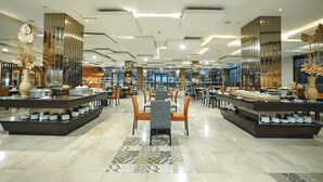 Eine großzügige Hotelhalle mit modernem Design, einer zentralen Sitzgruppe und einem Frühstücksbuffet.