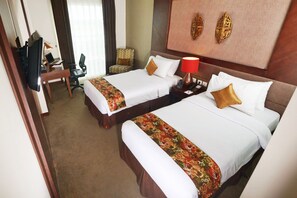 A hotel room with two beds, a desk with a laptop, a chair, and a TV.