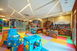 Uma área de recreação infantil com estruturas coloridas, um escorrega e uma casinha.