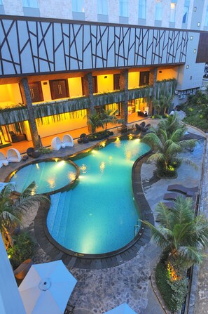 Un hôtel doté d’une grande piscine extérieure, de plusieurs espaces de détente et d’une façade bien éclairée.