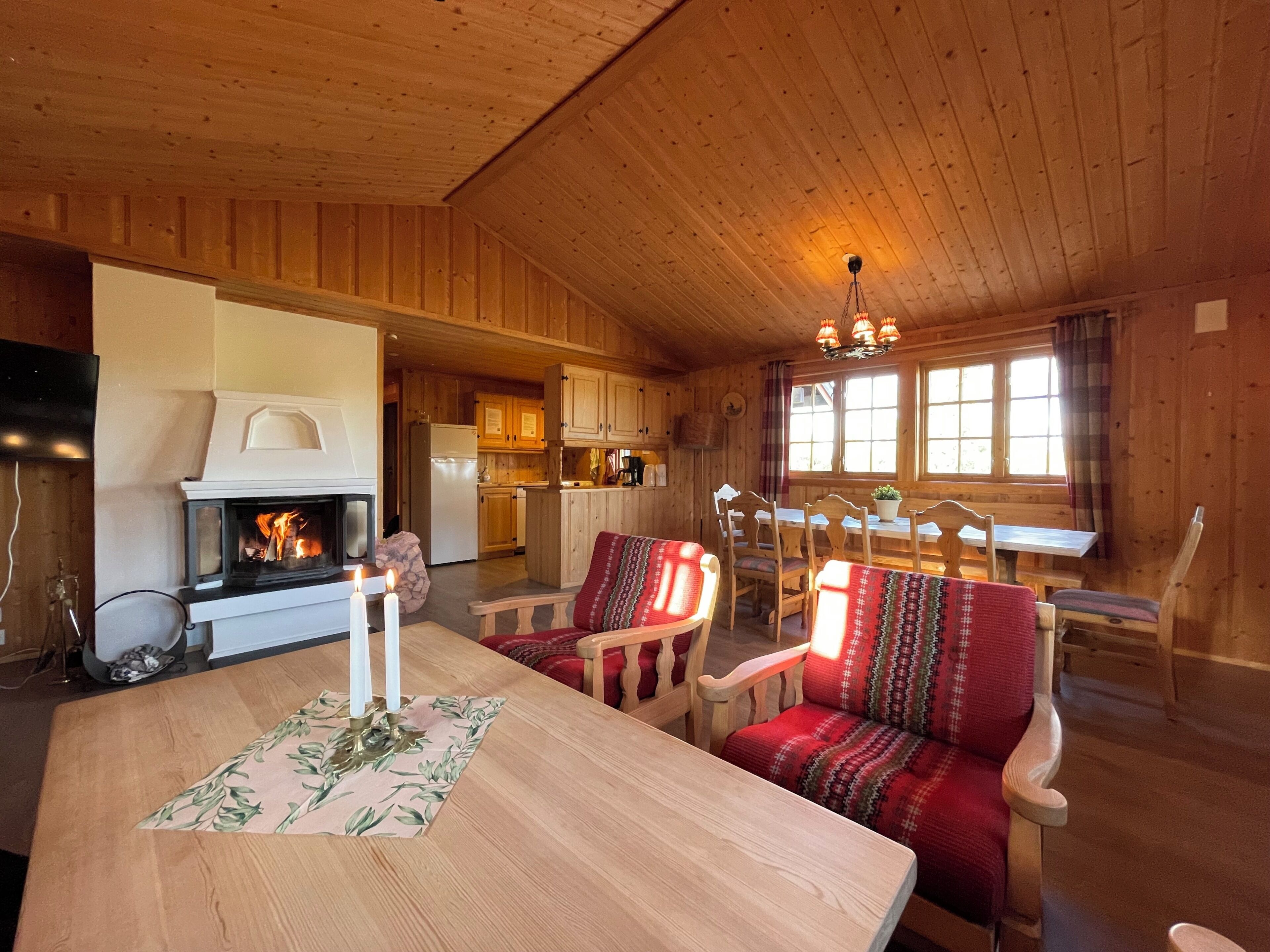 Interior acogedor de una cabaña con chimenea, una mesa de comedor de madera y asientos cómodos.