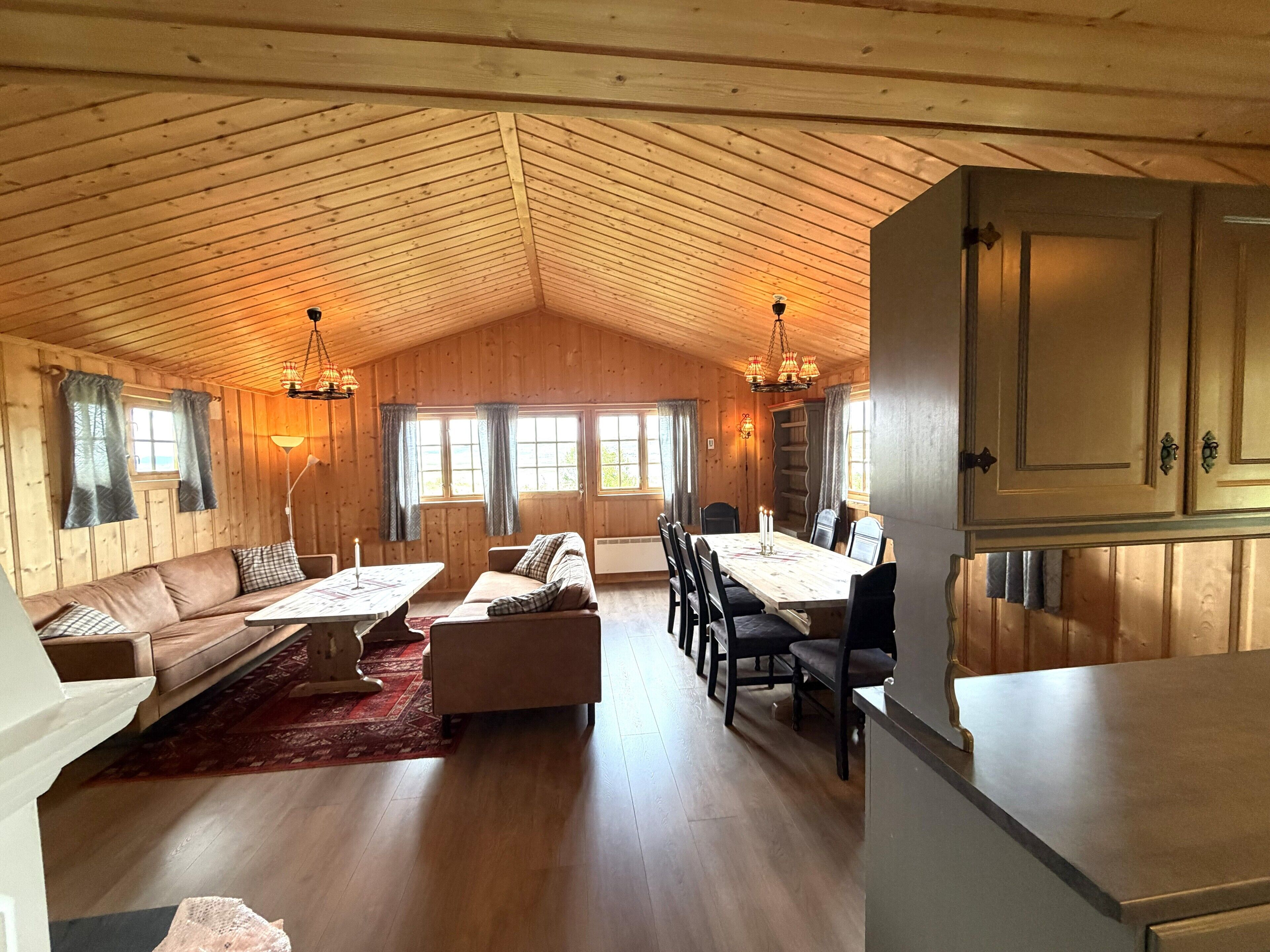 Una habitación amplia con techo de madera, una mesa de comedor con sillas, un sofá y una chimenea.