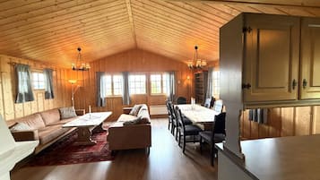 Una habitación amplia con techo de madera, una mesa de comedor con sillas, un sofá y una chimenea.