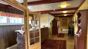 A cozy interior with a wooden reception desk, a brick fireplace, and a red carpet leading to a staircase. - Torsetlia Fjellstue og Hyttegrend (Nore og Uvdal)