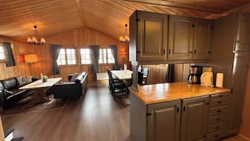 Un interior acogedor estilo cabaña, con comedor, cocina y zona de estar.