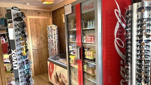 A store with a Coca-Cola refrigerator, a display of sunglasses, and a vending machine. - Torsetlia Fjellstue og Hyttegrend (Nore og Uvdal)