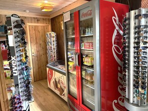 Un negozio con un frigorifero Coca-Cola, un espositore di occhiali da sole e una macchina distributrice.