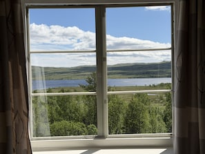 Una ventana con vistas a un lago y colinas.