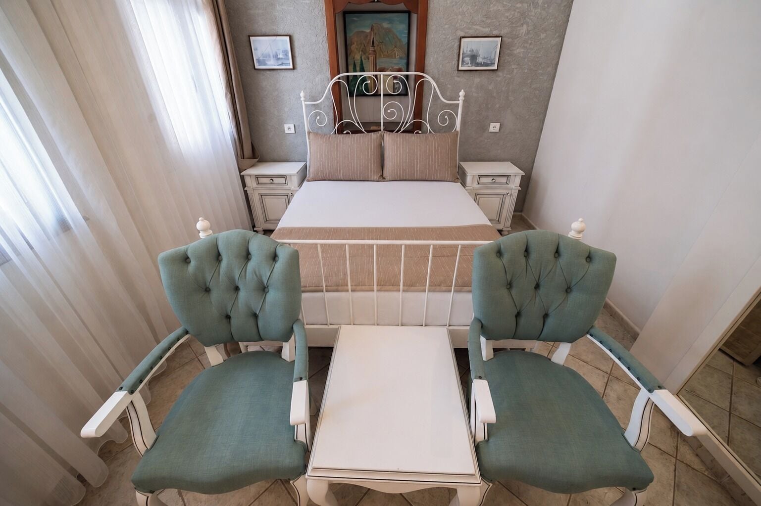 Ein Schlafzimmer mit einem Bett, zwei Stühlen, einem Nachttisch und einem kleinen Tisch.