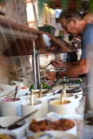 Une personne qui sert des plats dans un buffet proposant différents mets et différents ustensiles.
