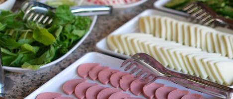 Una mesa de buffet con diversos alimentos y utensilios.