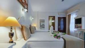 Una habitación de hotel con cama, lámpara de noche y televisión.