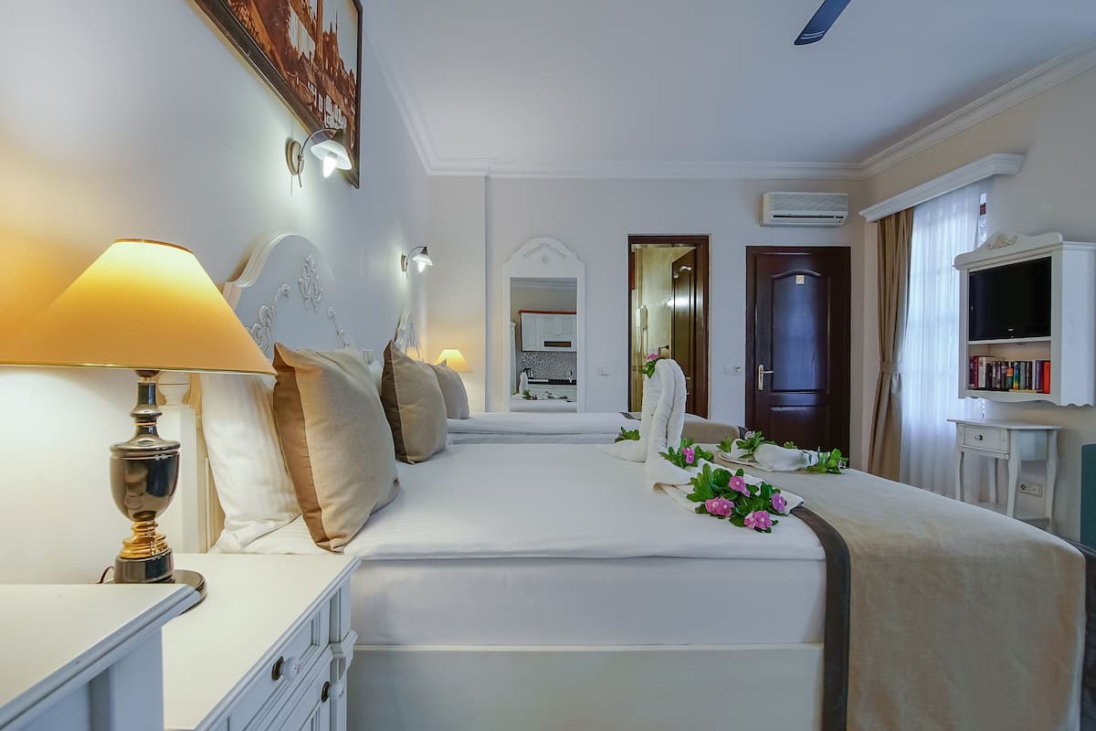 Una habitación de hotel con cama, lámpara de noche y televisión.