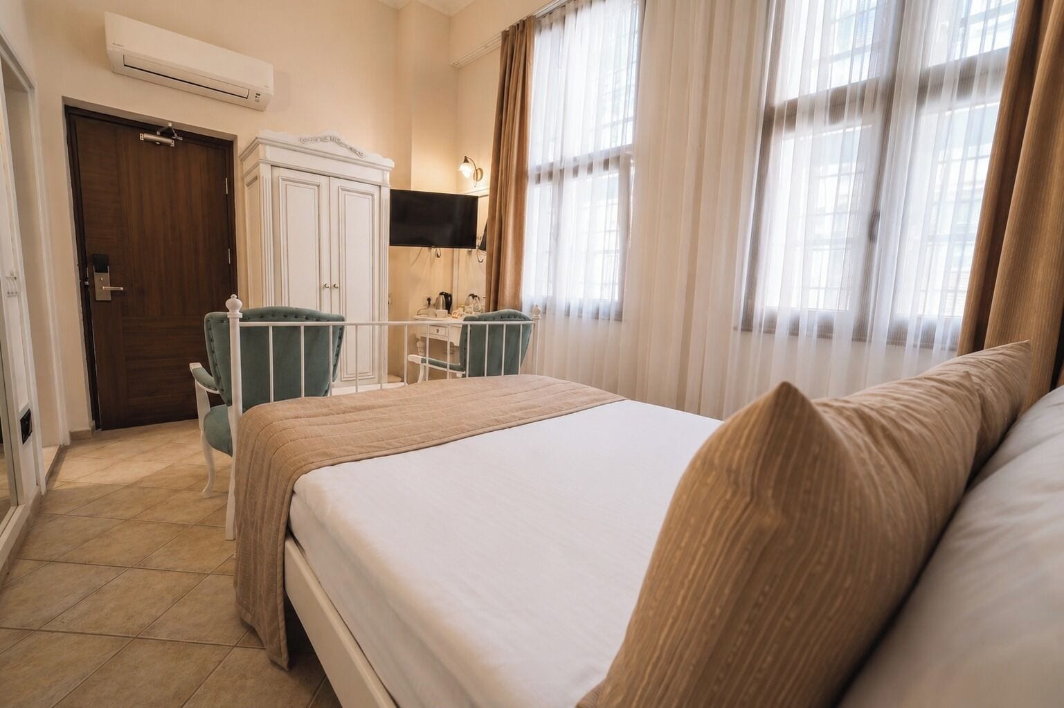 Een hotelkamer met een bed, een bureau, een stoel, een kledingkast en een televisie.