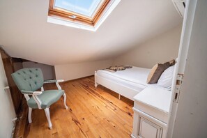 Un apartamento pequeño de una sola habitación con techo inclinado, una cama, una silla y un tragaluz.