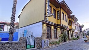 Un hotel con fachada amarilla, paredes de piedra y una calle empedrada.