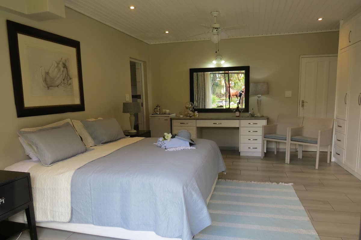 A bedroom with a bed, a desk, a chair, a dresser, and a mirror.
