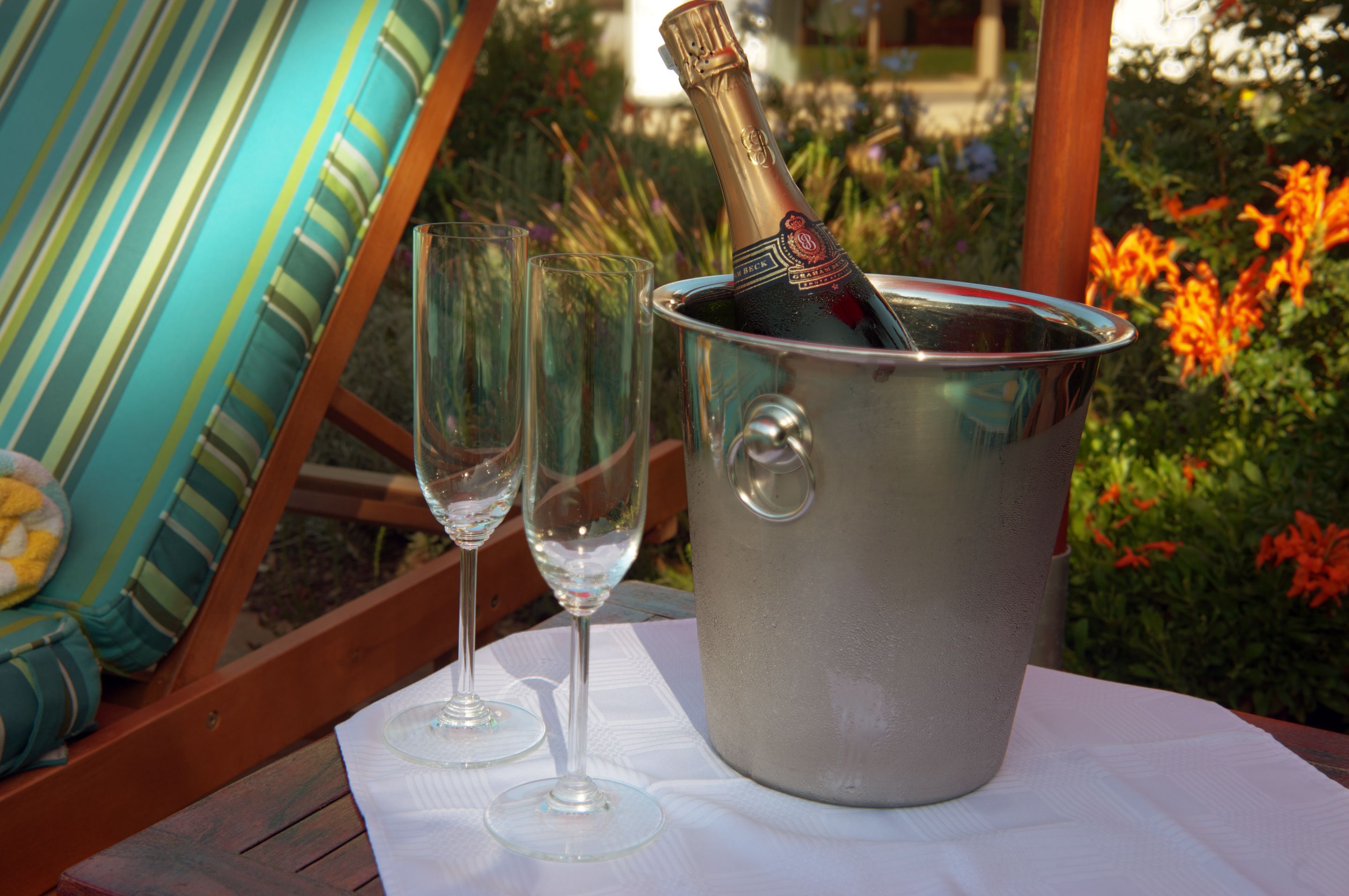 Eine Champagnerflasche in einem Metallkübel auf einem Tisch mit zwei leeren Weingläsern.