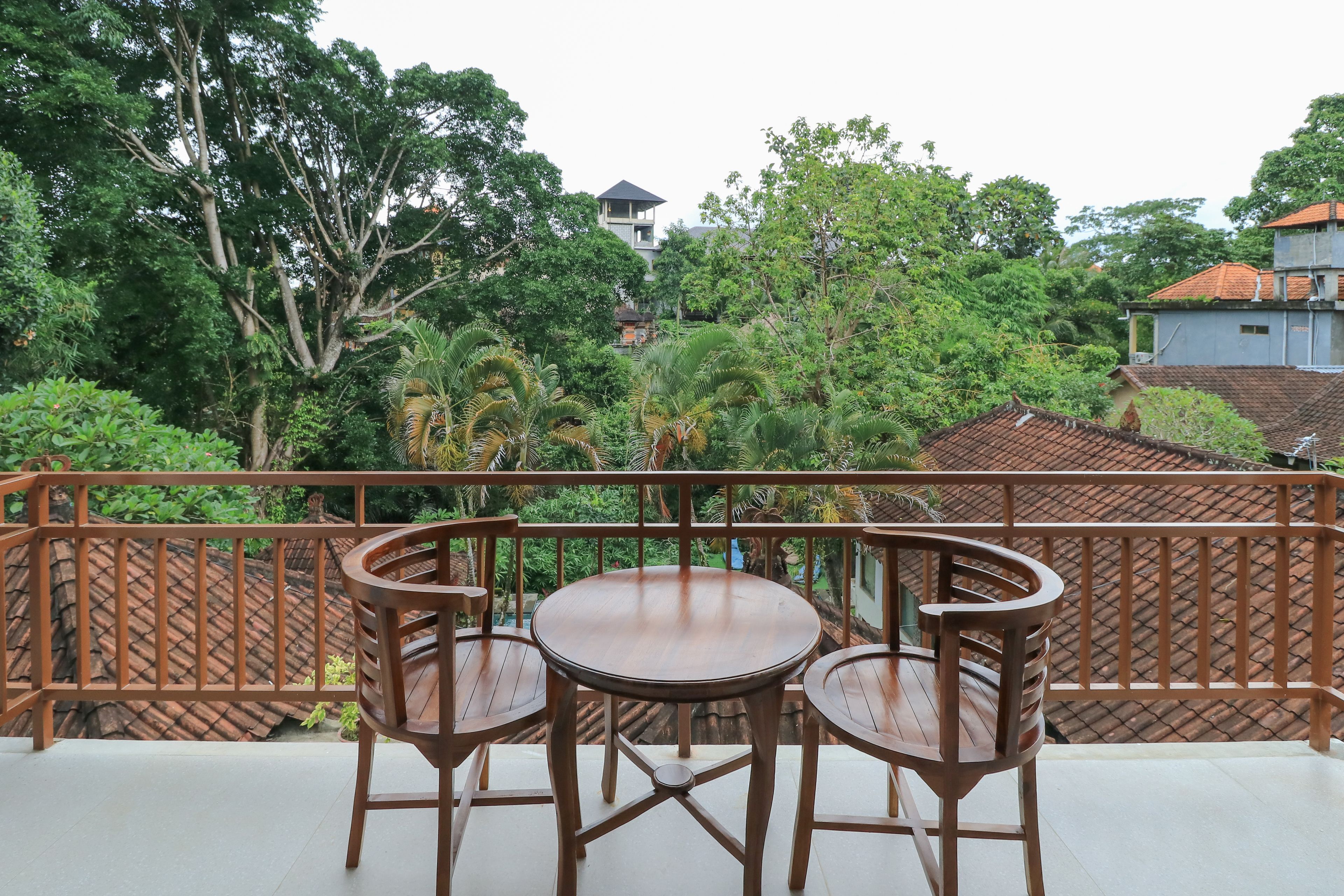 A balcony with a round wooden table and four chairs, surrounded by a wooden lattice railing.