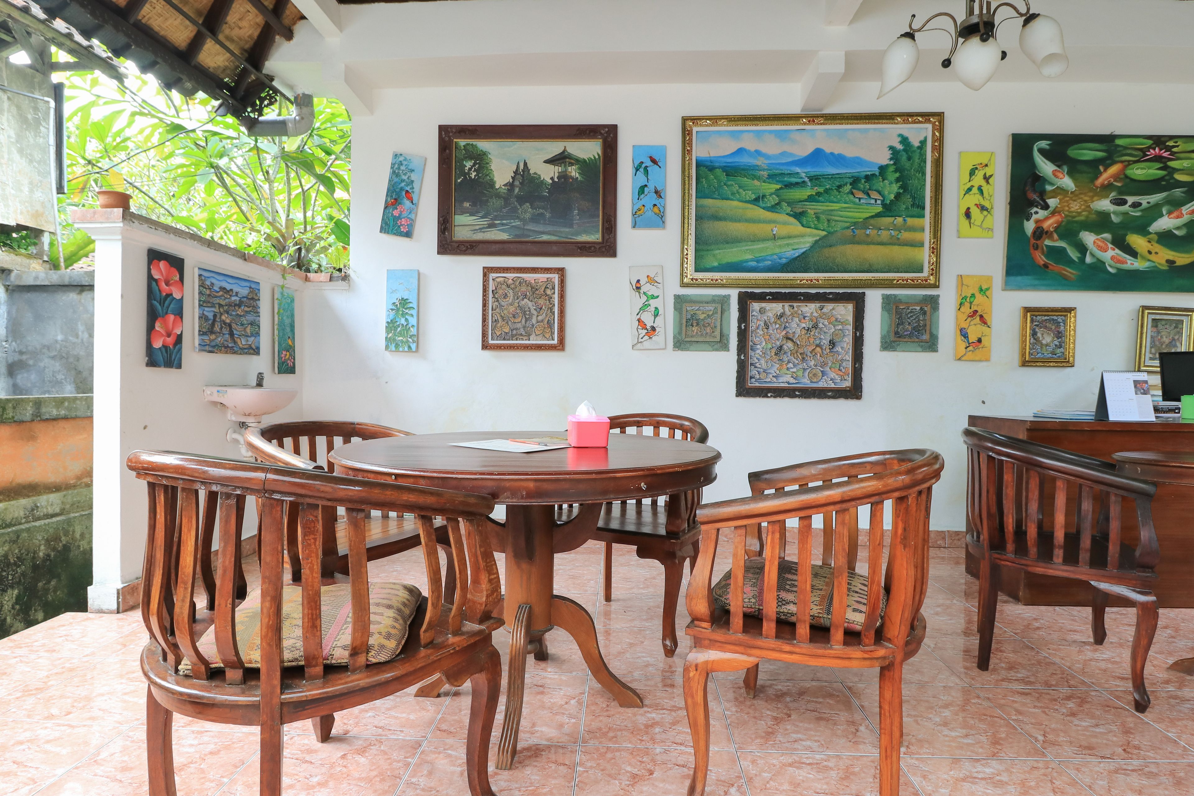 A dining area with a round wooden table and chairs, surrounded by various framed artworks on the walls.