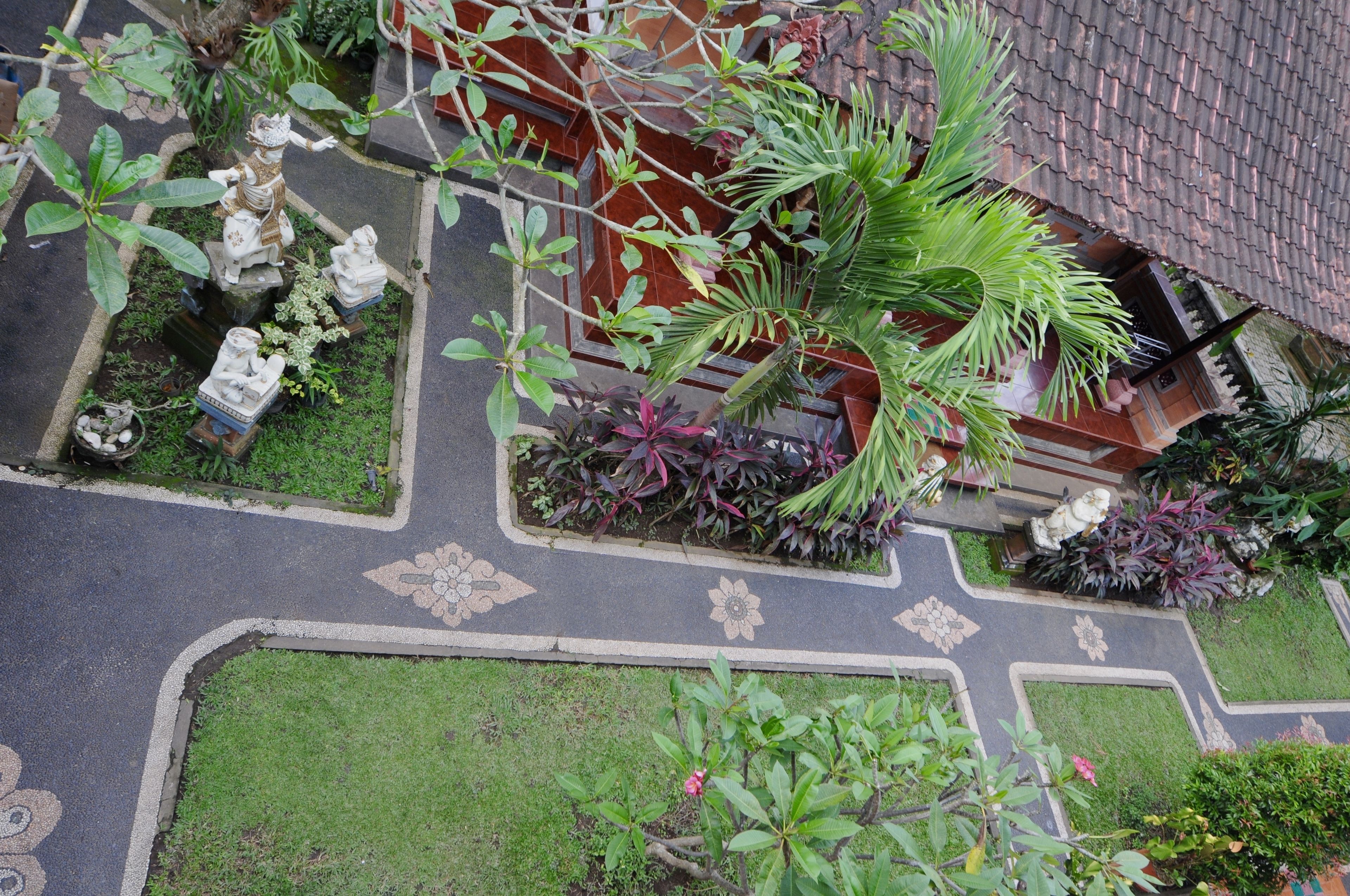 A courtyard with statues, plants, and a tiled roof.