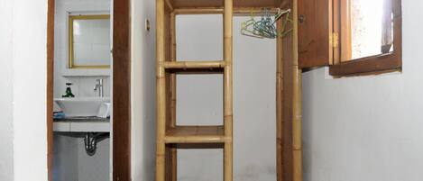 A bathroom with a bamboo shelf unit, a mirror, and a sink.