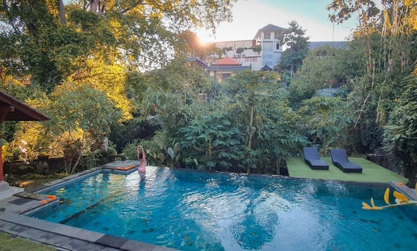 Una piscina al aire libre, sillones reclinables de piscina
