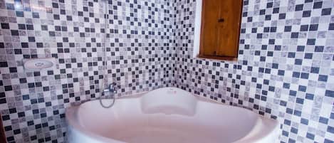 Un baño con pared de baldosas a cuadros, una bañera blanca y un mueble de madera.