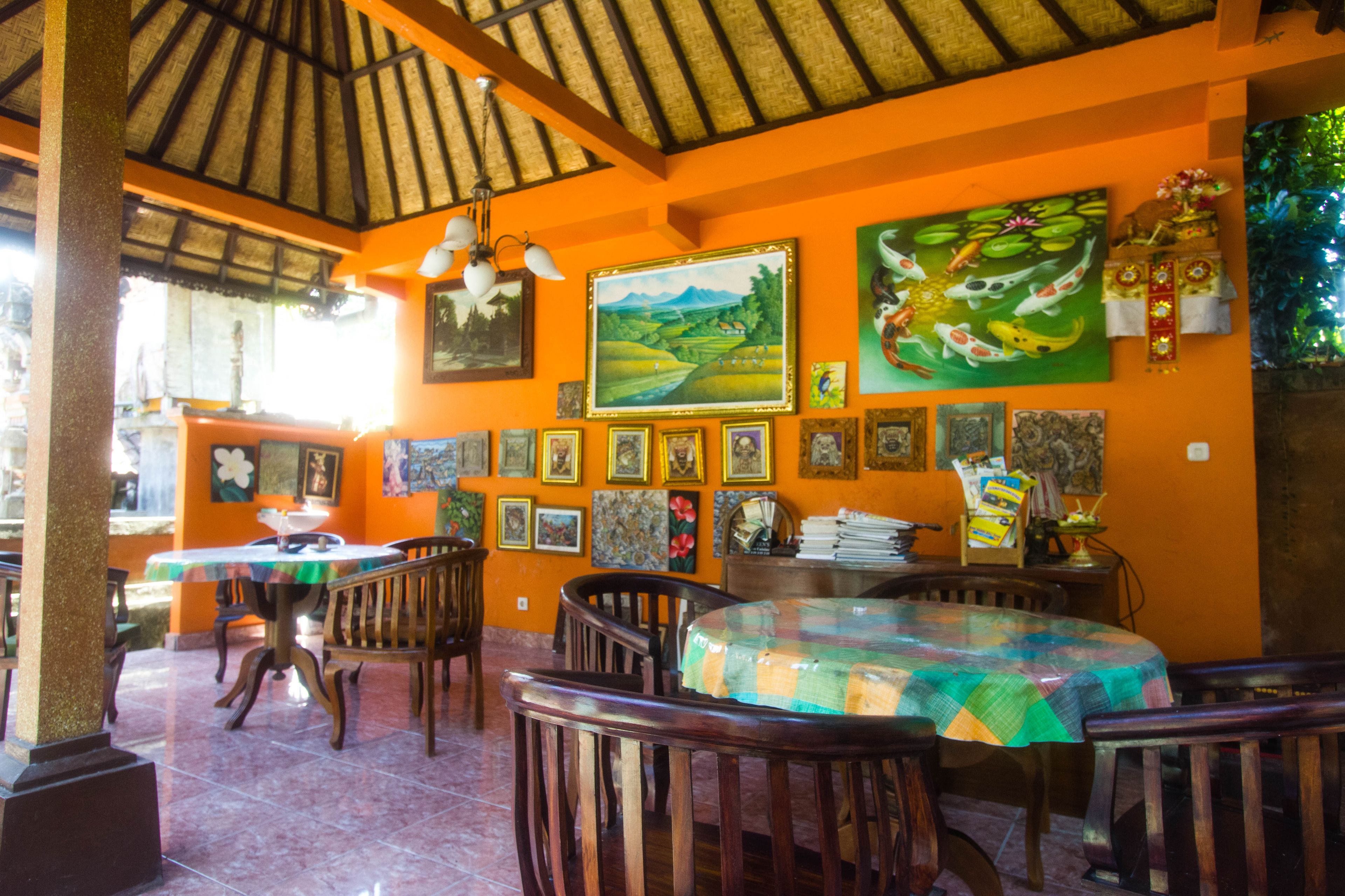 Un restaurante con muebles de madera, techo de paja y varias pinturas en las paredes.