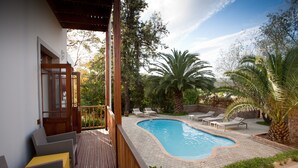 A wooden deck with a swimming pool, lounge chairs, and a view of the surrounding garden. - The Queen of Calitzdorp (Calitzdorp)