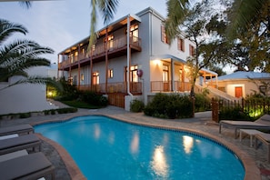 A two-story building with a swimming pool, outdoor seating, and a covered staircase.
