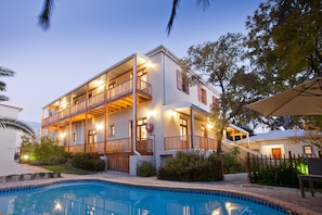 A two-story building with a swimming pool, balconies, and a staircase leading to the upper floor.
