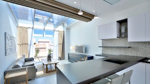 Una cocina moderna con una isla central, una zona de comedor con sofá y sillas, y un ventanal que proporciona luz natural.