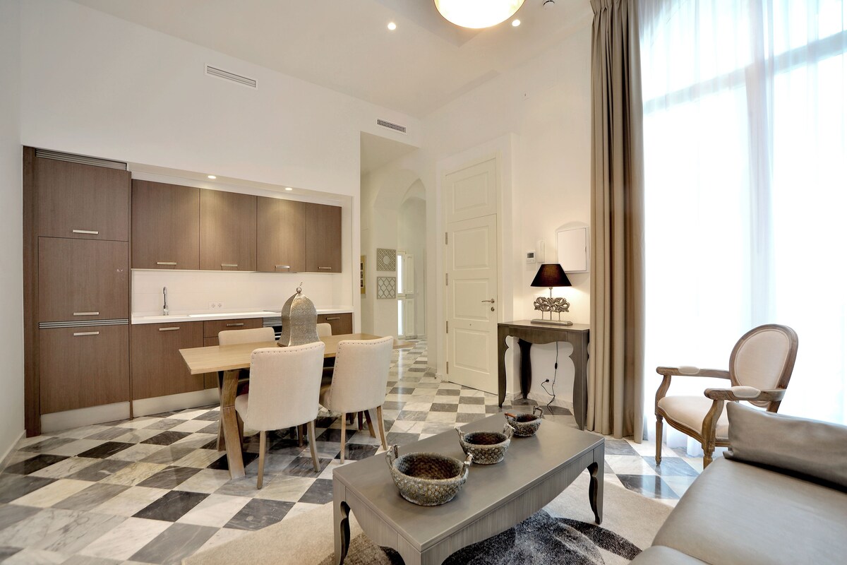 Una cocina moderna con armarios de madera, una mesa de comedor con sillas y piso a cuadros.