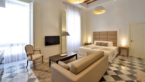 Una habitación de hotel con una cama grande, un sofá, un televisor y una araña.