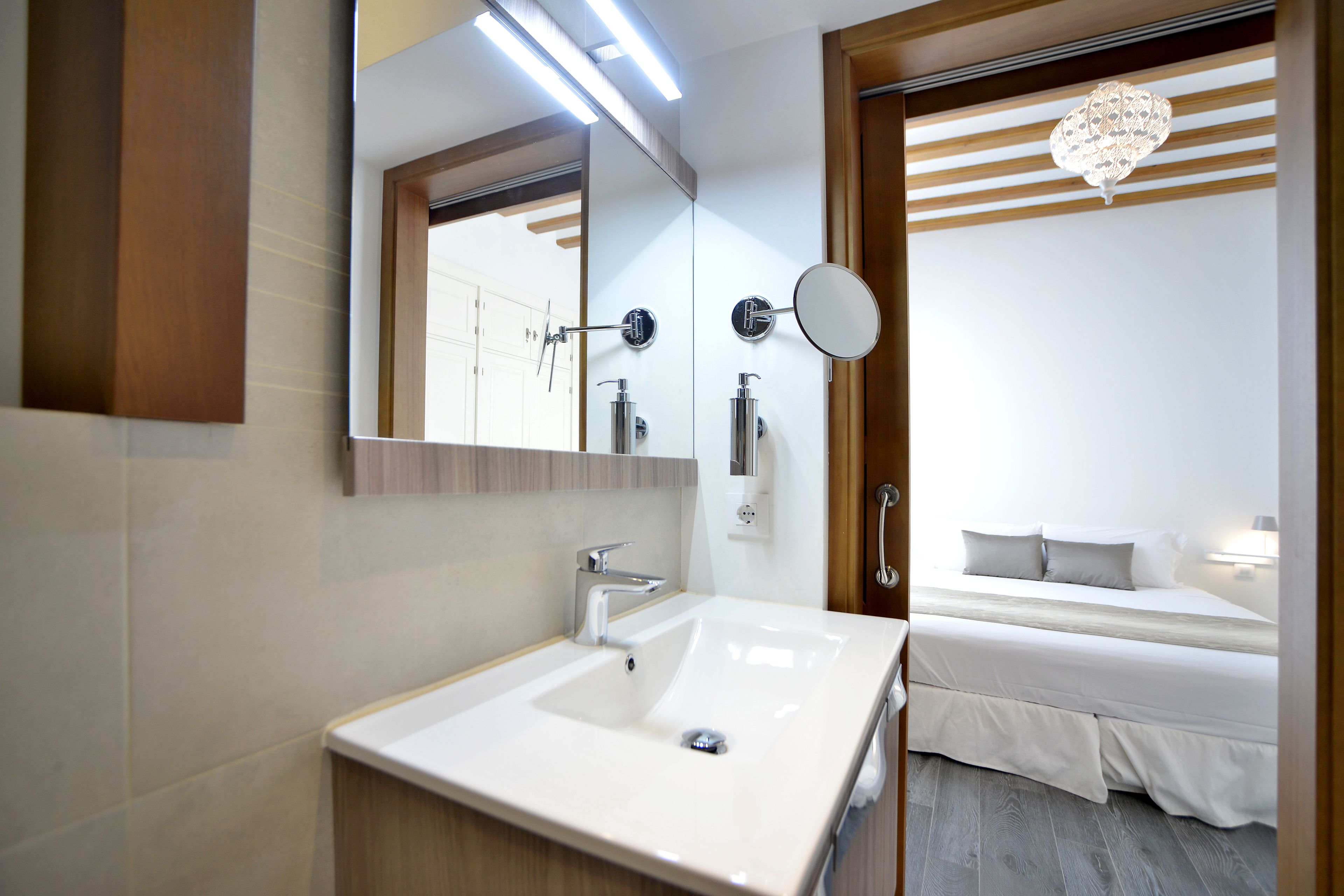Een moderne badkamer met een grote spiegel, een witte wastafel en een douche.
