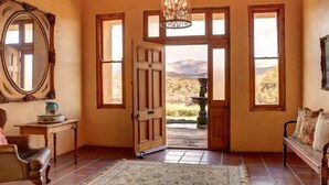 A room with a large wooden door, a bench, a table, and a mirror. - Keurfontein Country House (Willowmore)