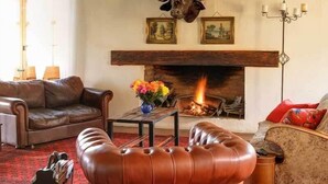 A cozy living room with a fireplace, leather furniture, and a bull head decoration. - Keurfontein Country House (Willowmore)