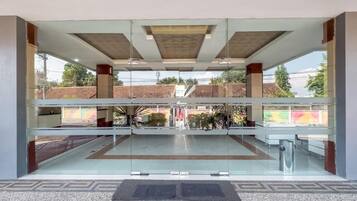 A modern building with a glass entrance, a patterned floor, and a view of the surrounding area.