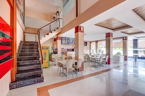 A spacious lobby with a staircase, multiple seating areas, and a coffee shop. - Tembok Batu Residence (Pogung Lor)