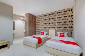 A hotel room with two beds, a wardrobe, a vanity, and a patterned wall. - Tembok Batu Residence (Pogung Lor)