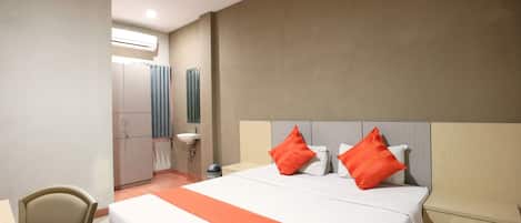 A hotel room with a bed, a desk, a chair, a wardrobe, and a bathroom.